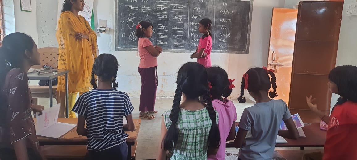 Teacher in yellow saree conducting interactive classroom session with students at blackboard